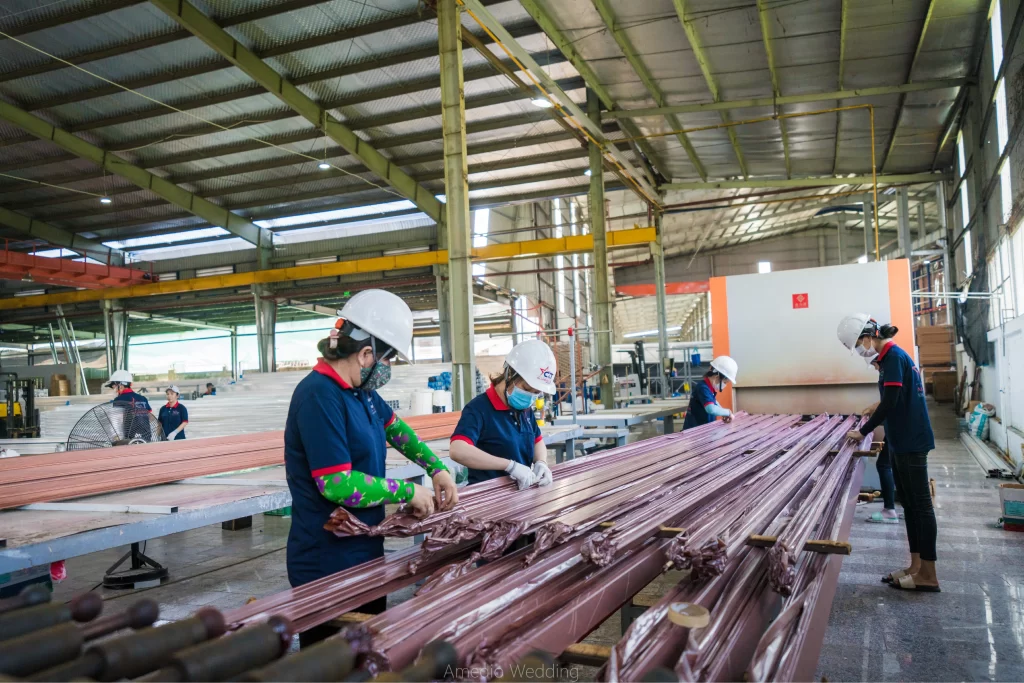 Công nhân tại Nhà máy Nhôm Cầu Thịnh đang thực hiện công đoạn phủ sơn vân gỗ cho các thanh nhôm trên dây chuyền sản xuất.