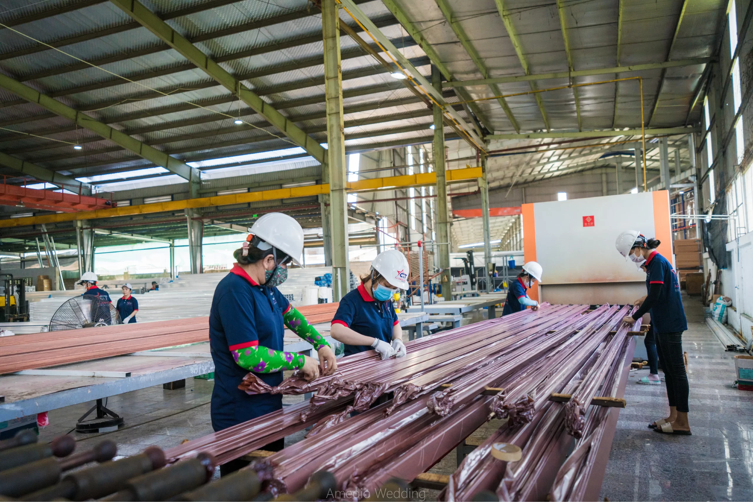 Công nhân tại Nhà máy Nhôm Cầu Thịnh đang thực hiện công đoạn phủ sơn vân gỗ cho các thanh nhôm trên dây chuyền sản xuất.